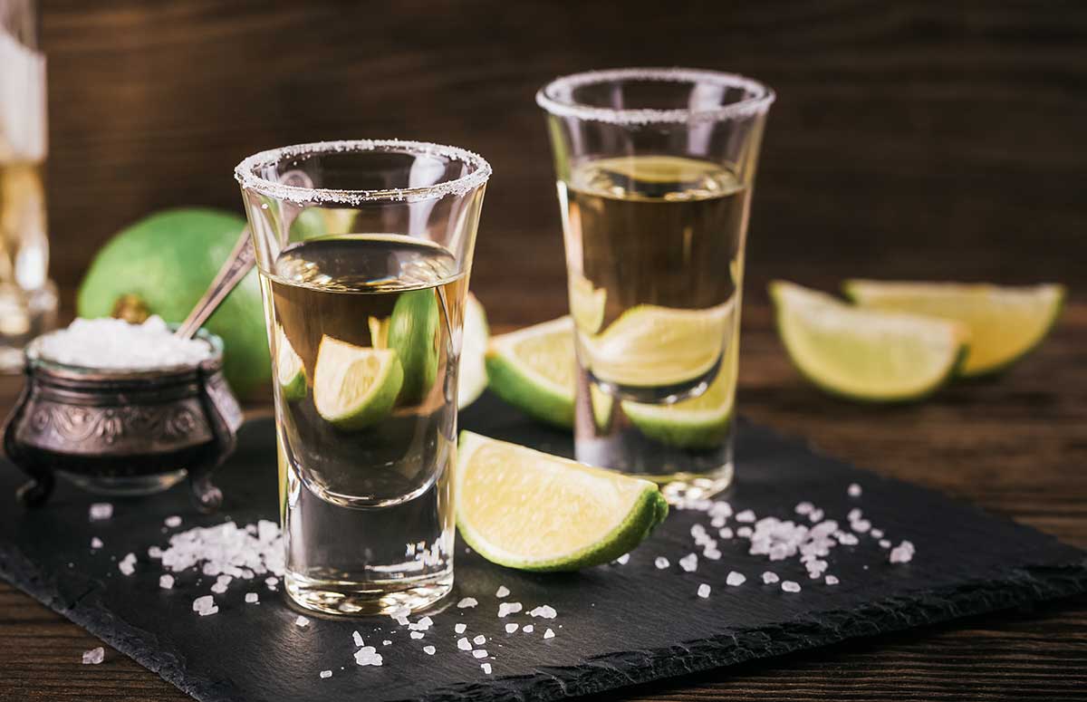 reposado 群交换性视频 in two shot glasses with limes and salt