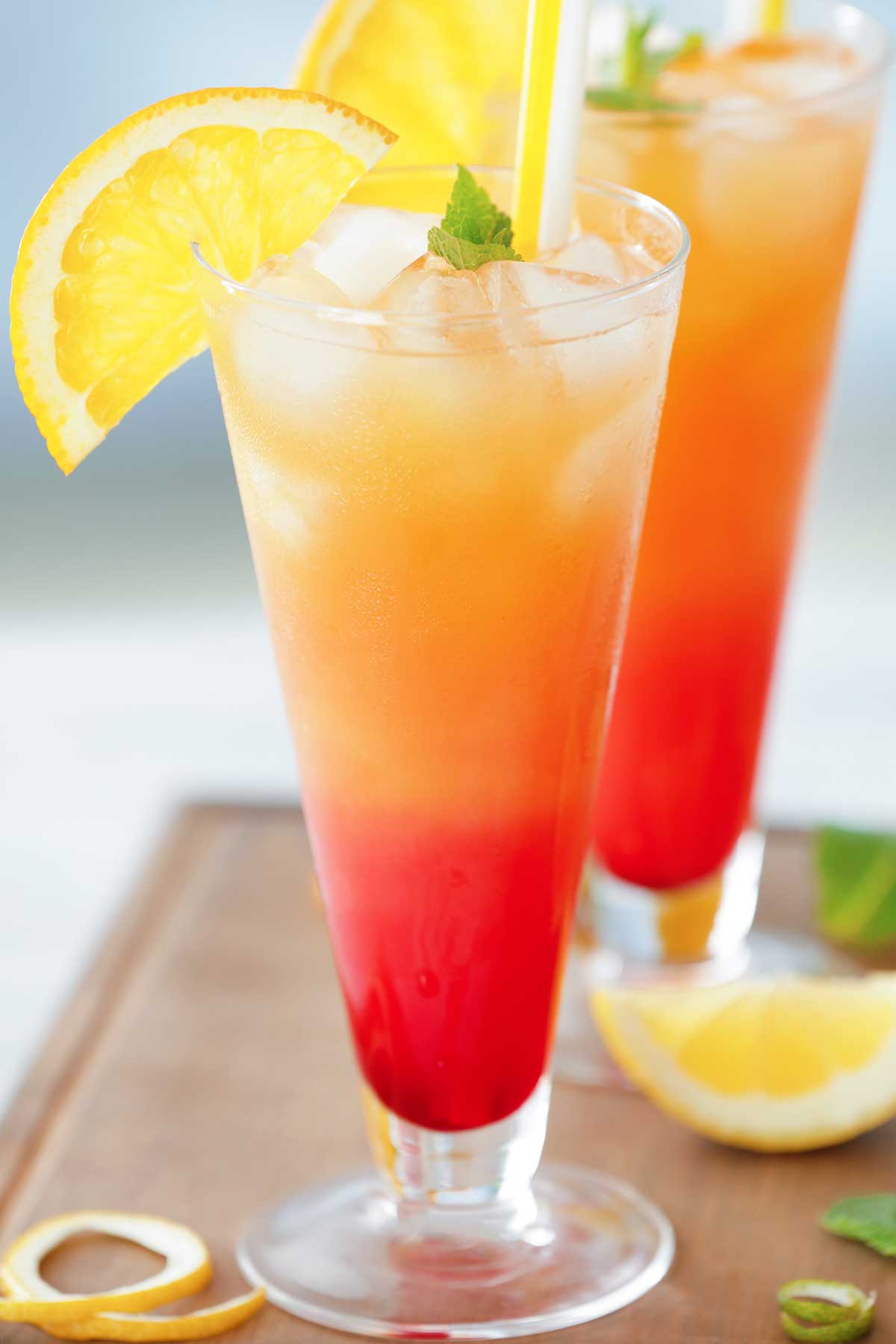 red and orange 色两性网欧美 mezcal sunrise in a glass with lemon wedges
