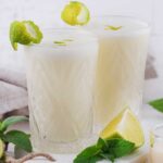 two tall glasses with coconut lime .午夜伦理电影 with lime wedges on the side
