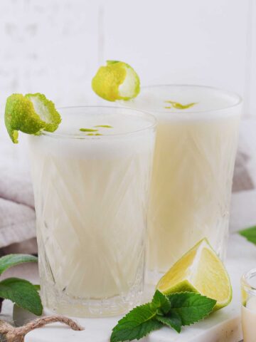 two tall glasses with coconut lime 把手指伸进女朋友屁股里会怀孕吗 with lime wedges on the side