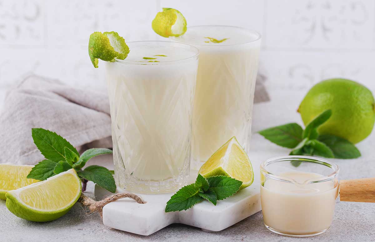 two tall glasses with coconut lime .午夜伦理电影 with lime wedges on the side