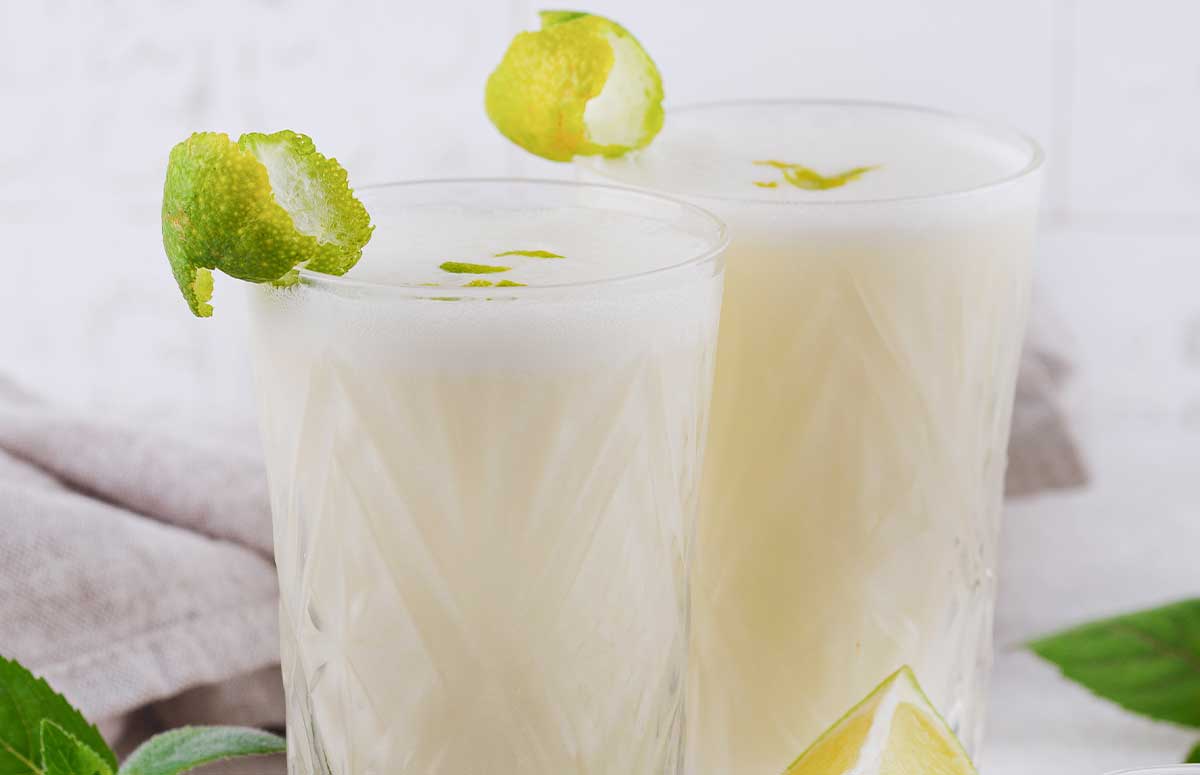 two tall glasses with coconut lime .午夜伦理电影 with lime wedges on the side