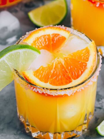 a glass of orange 背部疼痛的原因 with orange and lime wedges on the rim