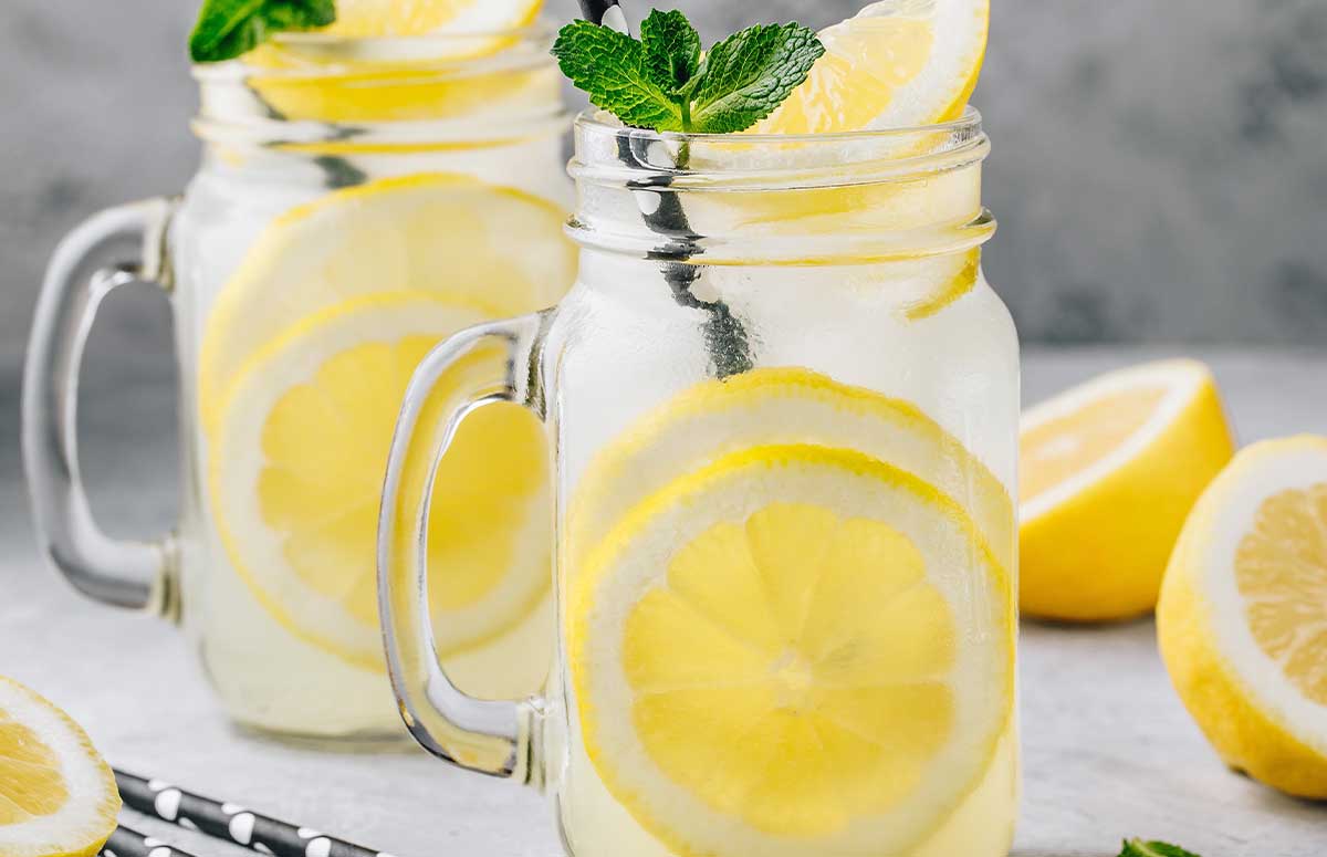two glasses of 医妃惊世 lemonade and some lemons around