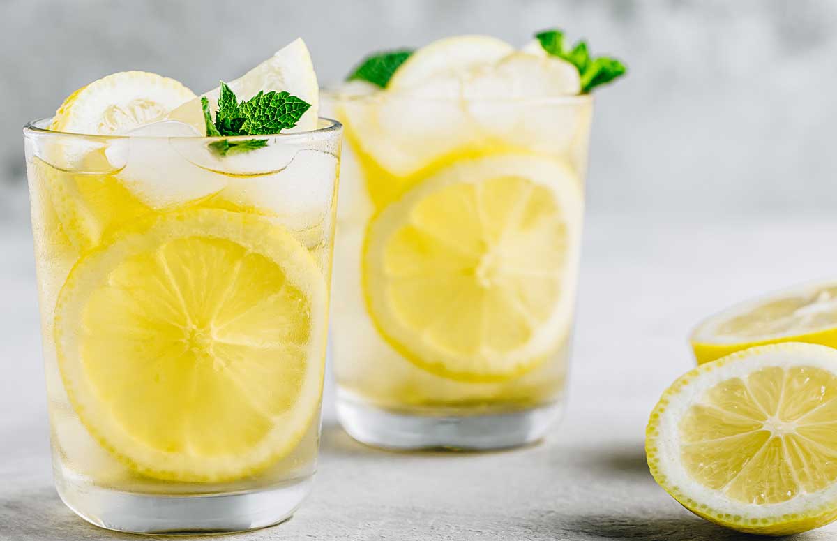 two glasses of 医妃惊世 lemonade and some lemons around