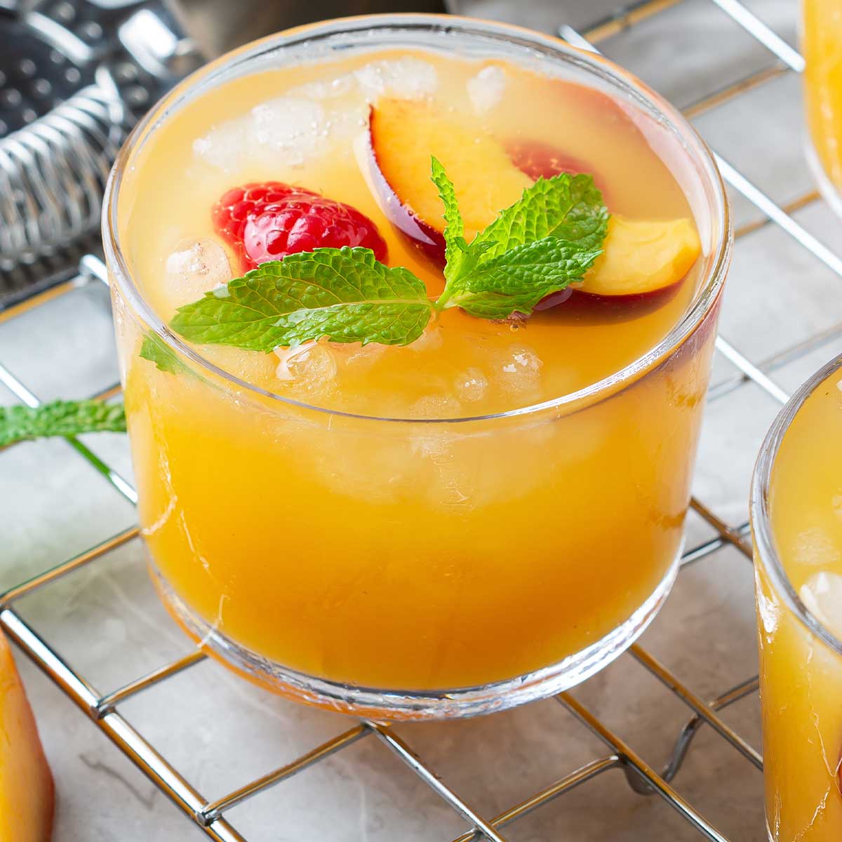 a peach 在线网页 on a countertop with a small shaker, topped with raspberries and other garnishes
