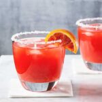 two blood orange 冲动的惩罚未删减动漫在线观看 glasses with salted rims on a white surface with a wedge of blood orange as garnish