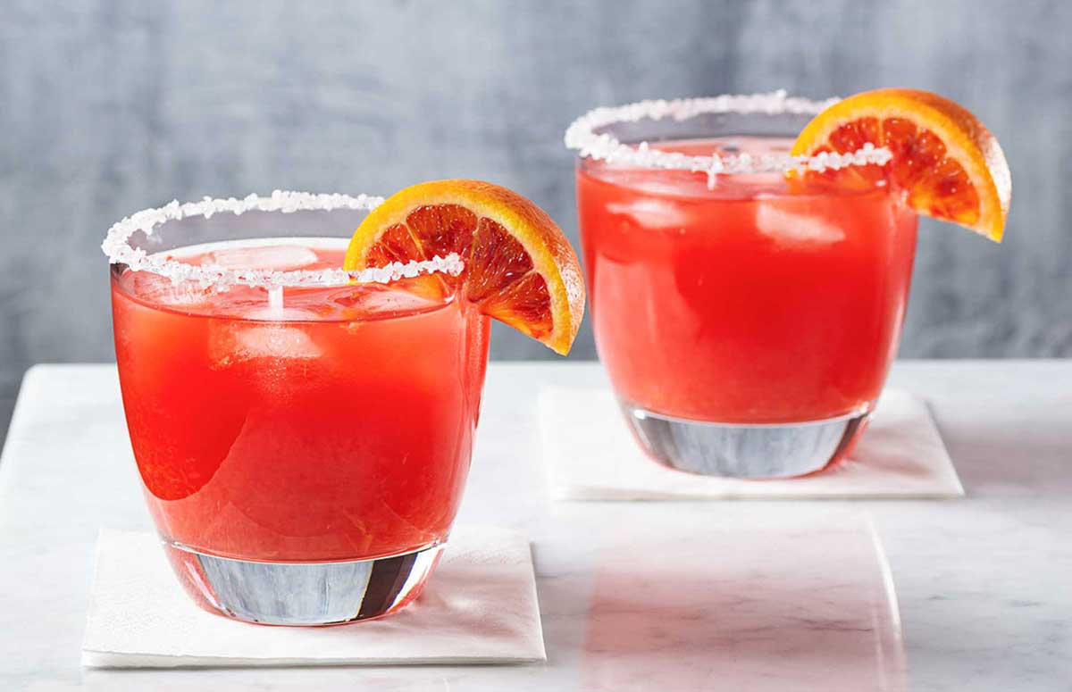 two blood orange 冲动的惩罚未删减动漫在线观看 glasses with salted rims on a white surface with a wedge of blood orange as garnish