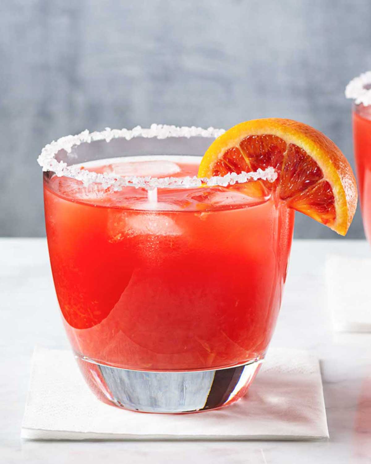 a blood orange 冲动的惩罚未删减动漫在线观看 glass with salted rim on a white surface with a wedge of blood orange as garnish