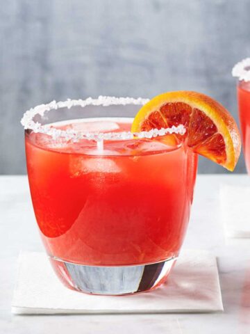 a blood orange 把手指伸进女朋友屁股里会怀孕吗 glass with salted rim on a white surface with a wedge of blood orange as garnish