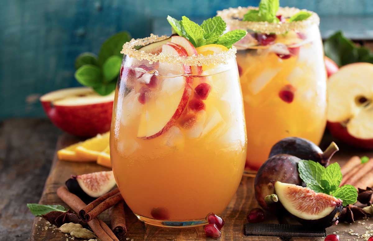 Two cinnamon sugar-rimmed glasses with Fall Sangria 丰满岳妇乱一区二区三区, apple slices, cinnamon sticks, sliced figs, and mint.