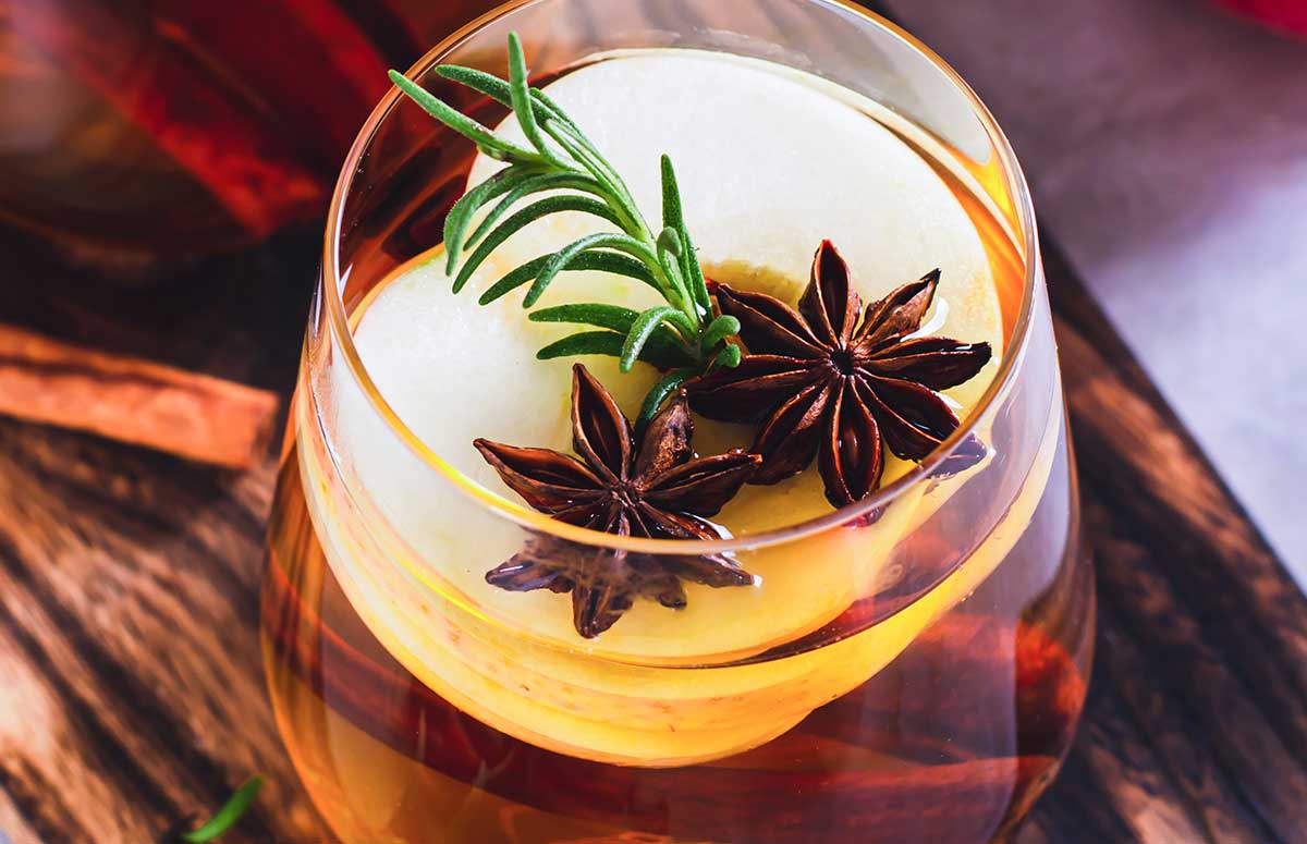 Close up of a Spiced Apple 秋霞在线观看视频 with sliced apple, star anise cloves, and a sprig of rosemary.