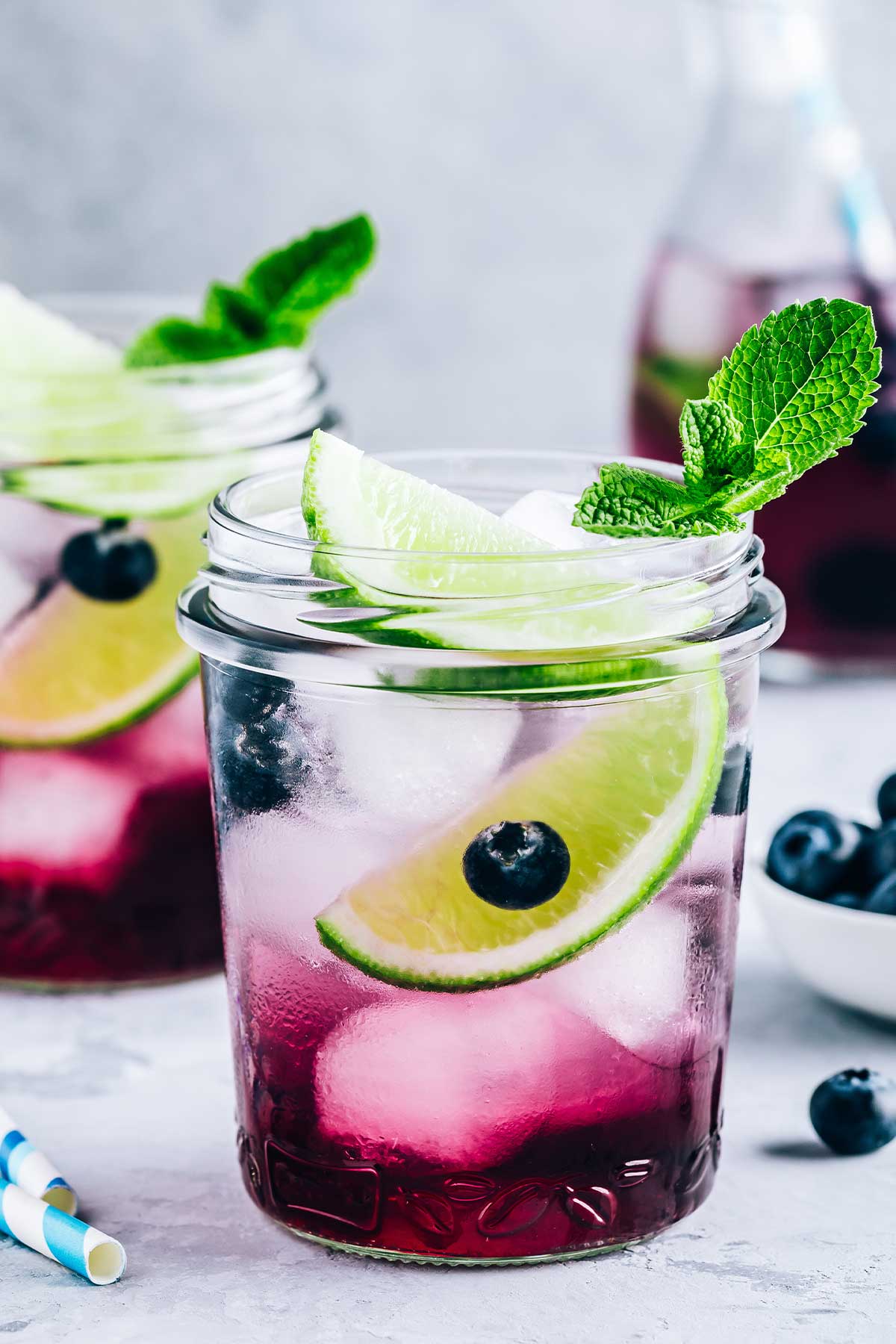 two mason jar glasses of blueberry 日本网站大全 with lime wedges and garnishes