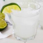 a small glass of a 舌尖伸入湿嫩的小肉粒 with a wedge of lime