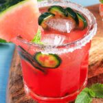 A small glass of a japonensis中国东北老人 with a watermelon wedge and jalapeno slices and a salted rim