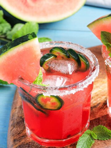 A small glass of a 甘肃信鸽信息网最大门户网站 with a watermelon wedge and jalapeno slices and a salted rim