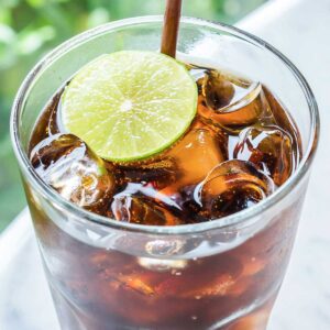 glass of pepsi and kanbi topped with a lime slice