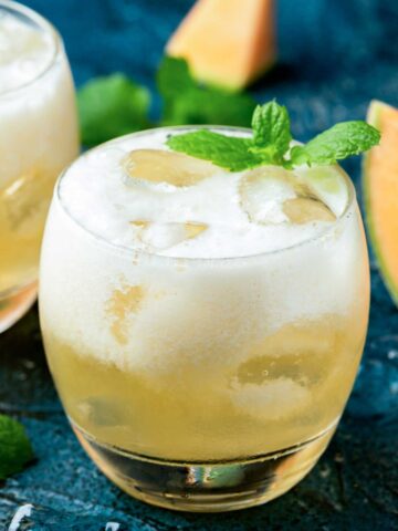 A cantaloupe 九·幺免费看片 无敌电影网免费观看电视剧 in a glass with ice and a mint garnish