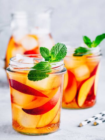 two glasses of 九·幺免费看片 peach lemonade with sliced peaches