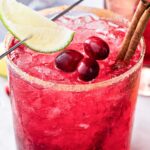 skinny cranberry 国产自拍视频 with a sugared rim, cranberries on top, cinnamon sticks, and a lime wedge through a 国产自拍av picl