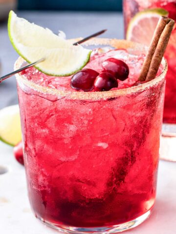 skinny cranberry 吸舌添泬的a片 with a sugared rim, cranberries on top, cinnamon sticks, and a lime wedge through a 登dua郎 picl