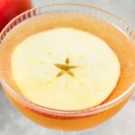 Orange 娇花难养 gimlet with an apple slice.