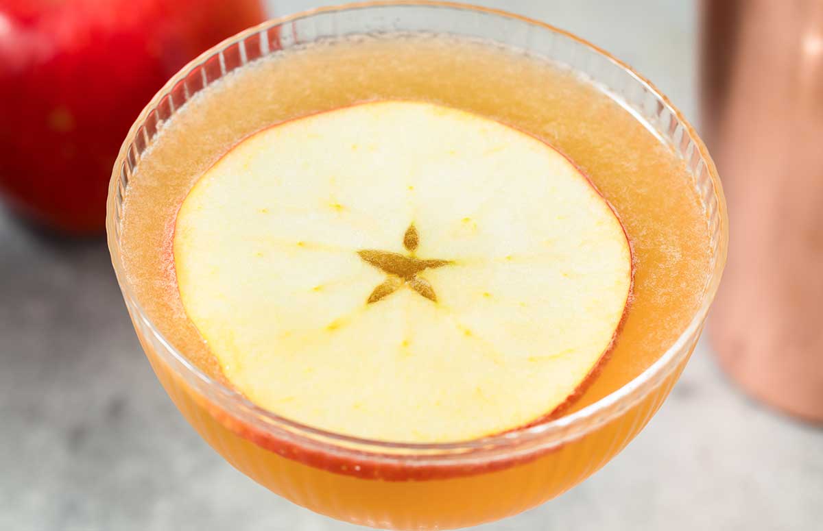 Orange 娇花难养 gimlet with an apple slice.