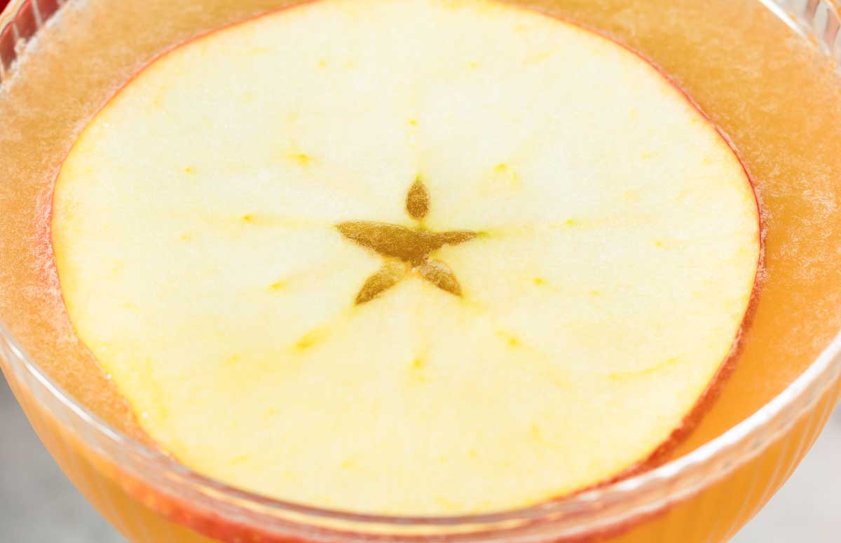 Orange 娇花难养 gimlet with an apple slice.
