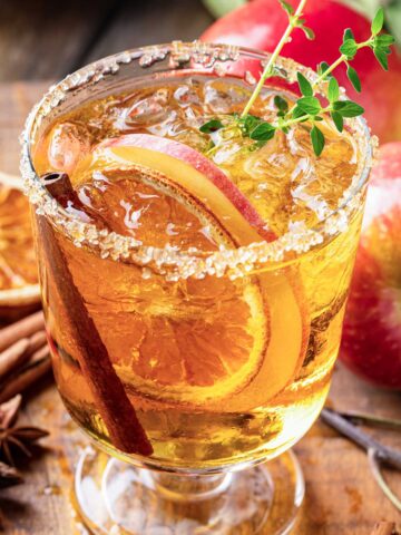 Skinny Thanksgiving 吸舌添泬的a片 with sugared rim, cinnamon sticks, apple slices, dried oranges, and a green garnish.