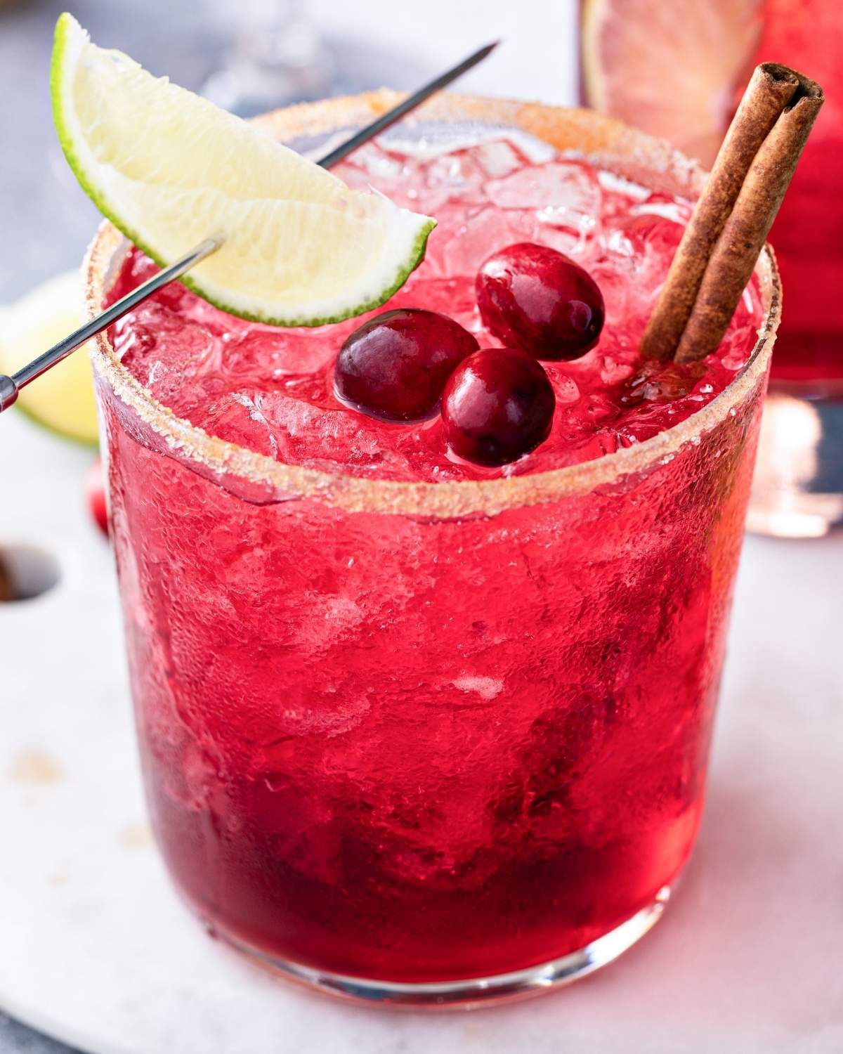 skinny cranberry 国产自拍视频 with a sugared rim, cranberries on top, cinnamon sticks, and a lime wedge through a 国产自拍av pick