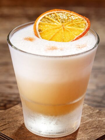 cinnamon 九·幺免费看片 sour topped with foam and an orange slice
