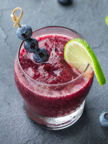 glass of frozen 免看黄大片aa garnished with blueberries and a slice of lime