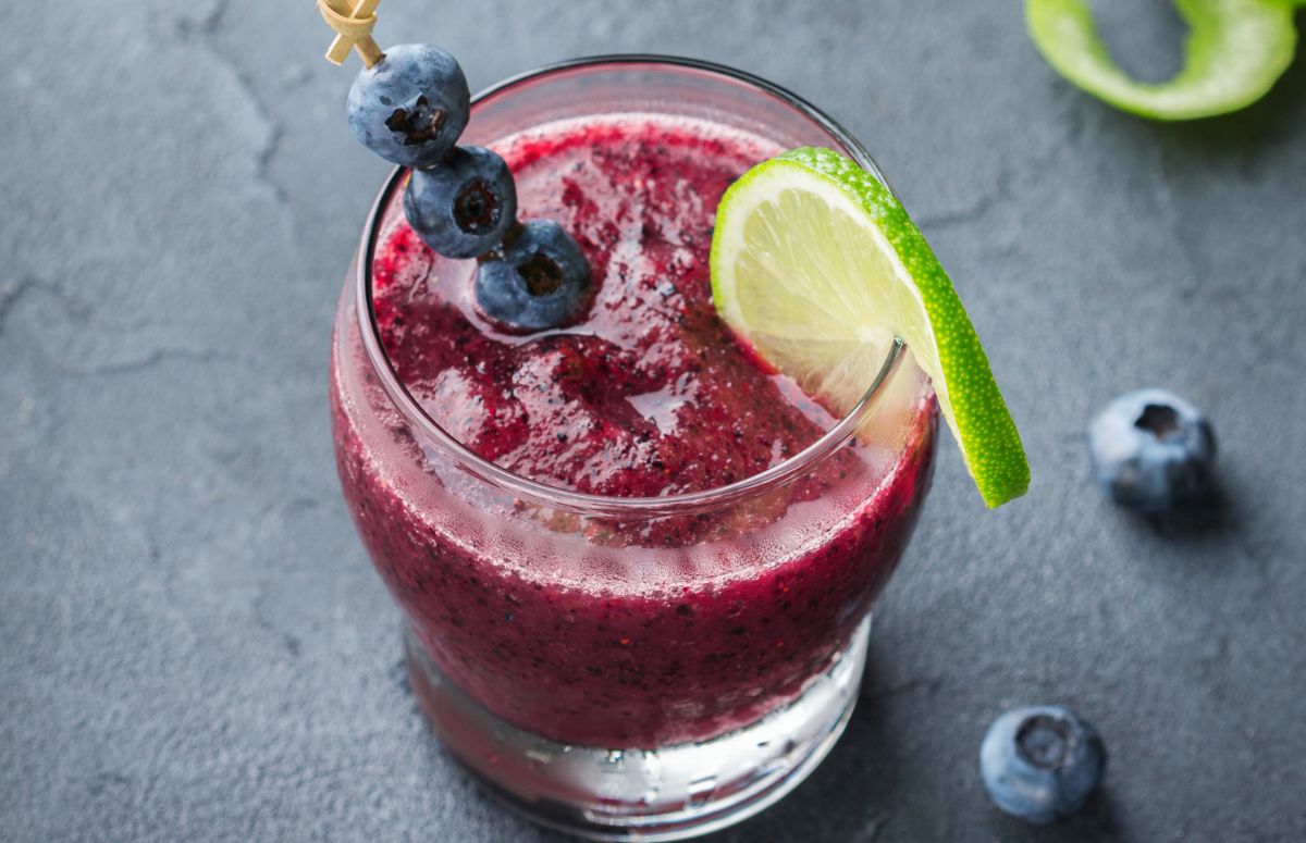 glass of frozen 推油少妇久久99久久99久久 garnished with blueberries and a slice of lime